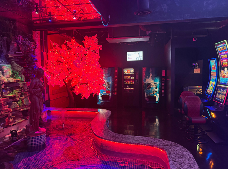 Neon-lit interior offeaturing glowing red LED tree, water feature, statue, and gaming machines